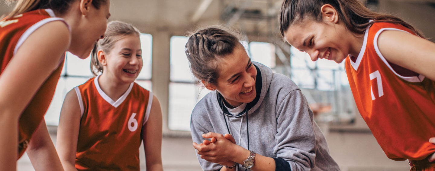 Female coach encouraging her girl basketball players