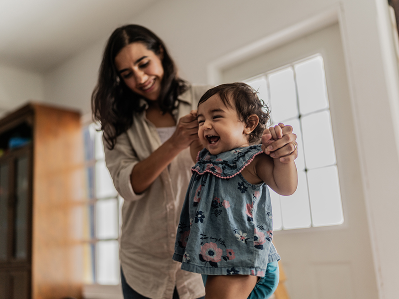 mom holding the hands of her laughing baby