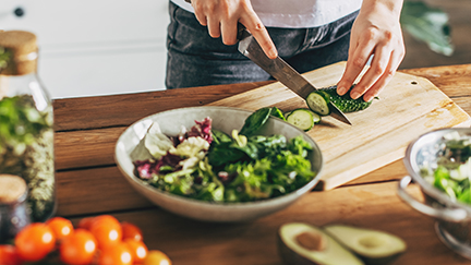 person cutting cucumbers for a salad