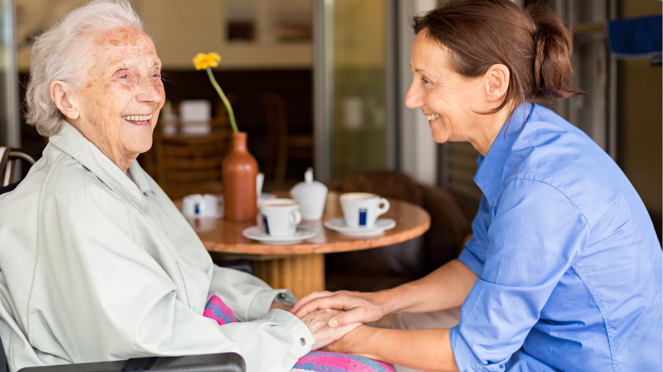 older woman and younger woman smiling and holding hands